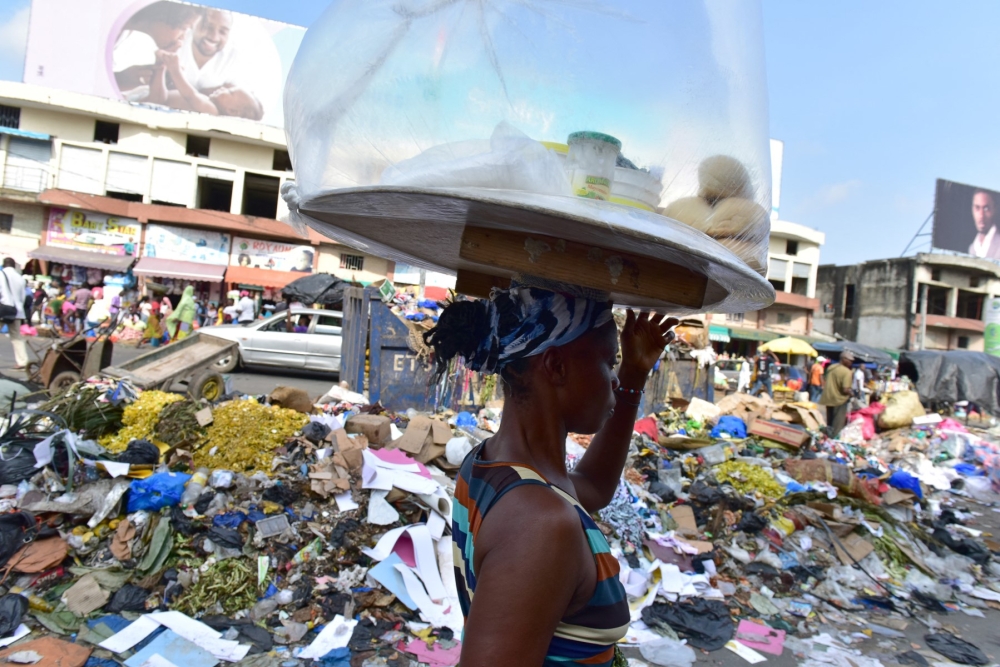 A street vendor walks past a trash heap at the market of Adjame, a working class neighbourhood of Abidjan, on August 10, 2017. — AFP pic 