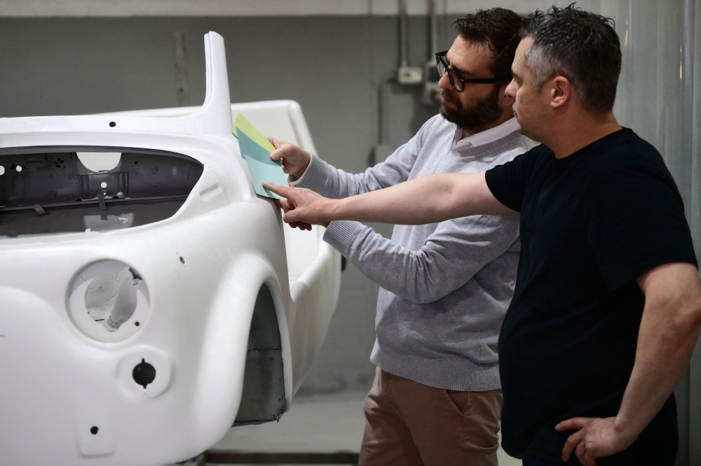 Owner of the Officine Gentile garage, Giovanni Gentile (R) and marketing manager Giorgio Pagliero decide on the color of a Fiat 500 model that will be transformed into an electric 500 Jolly Lido model at Officine Gentile in Turin on April 30, 2026. — AFP pic