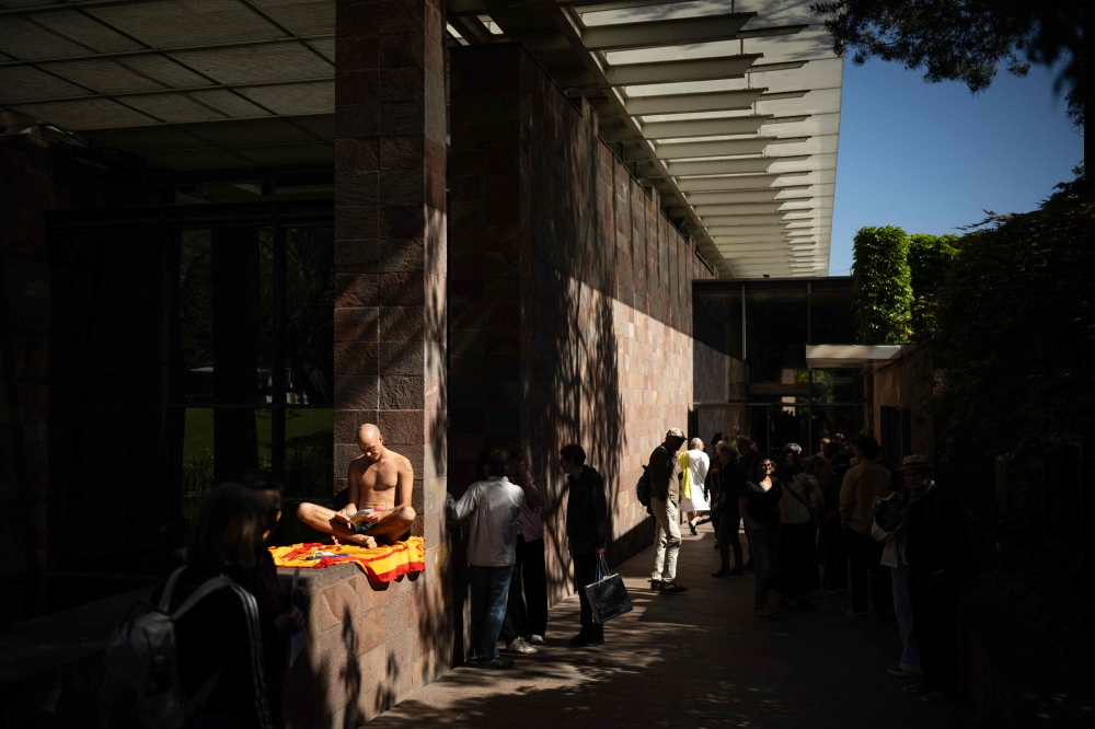 A visitor in swimsuit reads a book at the main entrance of the Beyeler Foundation during the experience called “bathers’ day” (“journée des baigneurs et des baigneuses”) inspired by Italian artist Maurizio Cattelan, on the occasion of the exhibition “Cezanne” of the French painter Paul Cezanne at the Beyeler Foundation in Riehen, northern Switzerland on May 1, 2026. — AFP pic