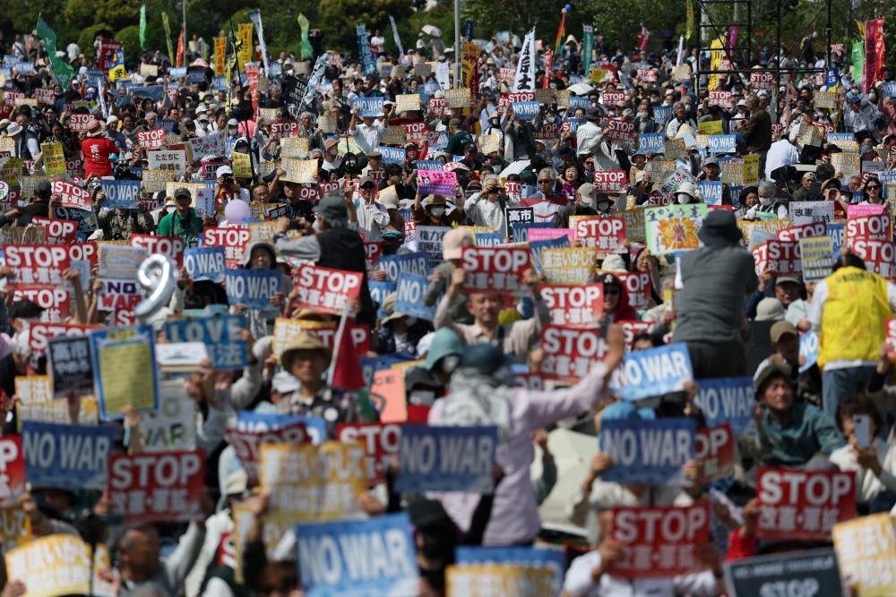 A demonstrator holds a paper fan featuring the number 9 referring to Article 9 of the Japanese Constitution, which renounces war as a sovereign right and prohibits the maintenance of armed forces, as people gather to protest demanding the resignation of Japan's Prime Minister Sanae Takaichi, opposing her policies on constitutional revision and military expansion, during a Constitution Memorial Day rally in Tokyo, Japan, May 3, 2026. — Reuters pic