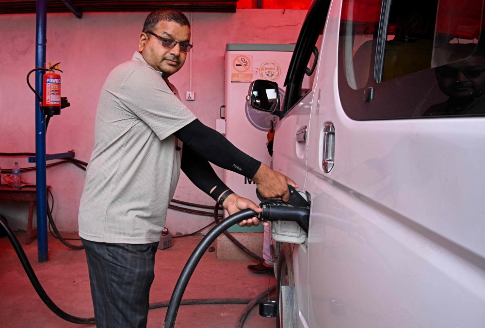 Electric microbus driver Purushottam Adhikari charges his vehicle at a charging station in Kathmandu on May 1, 2026. — AFP pic