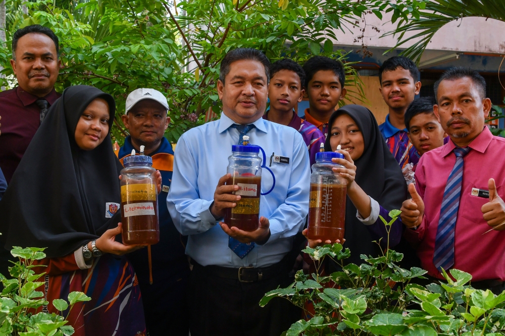 SMK Berangan students displaying stingless bee honey obtained after extracting it from the hive at the SMK Berangan Stingless Bee Sustainable Garden in Tumpat, Kelantan. With them is the school’s principal Kamarul Zaman. — Bernama pic 