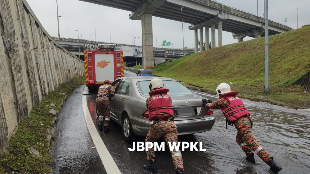 Firefighters help push a stalled car. — Picture from X/Bernama 