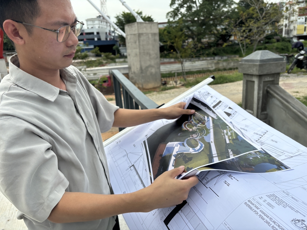 Project contractor Adam Cheah Zheng Yip shows the construction design of a new pedestrian bridge and riverfront development along Sungai Kinta near Hugh Low Street in Ipoh, Perak. — Picture by John Bunyan