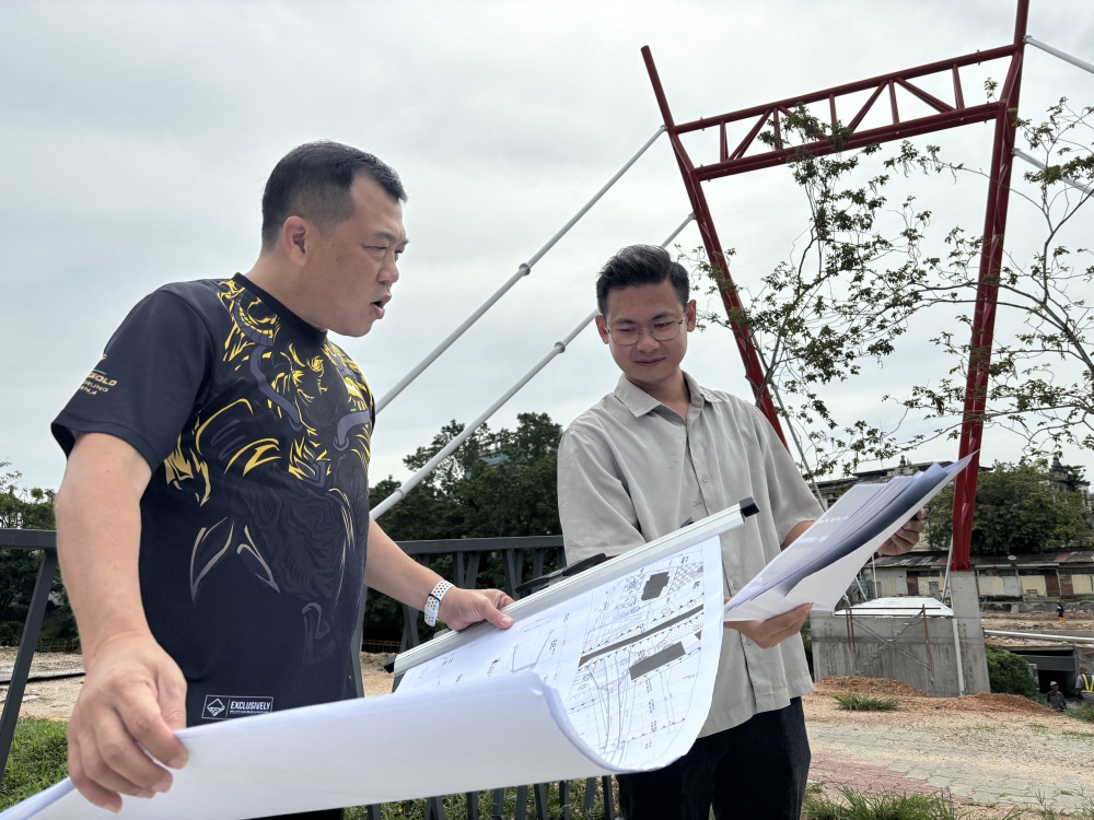 Perak Tourism, Industry, Investment and Corridor Development Committee chairman Loh Sze Yee (left) and project contractor Adam Cheah Zheng Yip (right) inspect the construction design at the project site of a new pedestrian bridge and riverfront development along Sungai Kinta near Hugh Low Street in Ipoh, Perak. — Picture by John Bunyan
