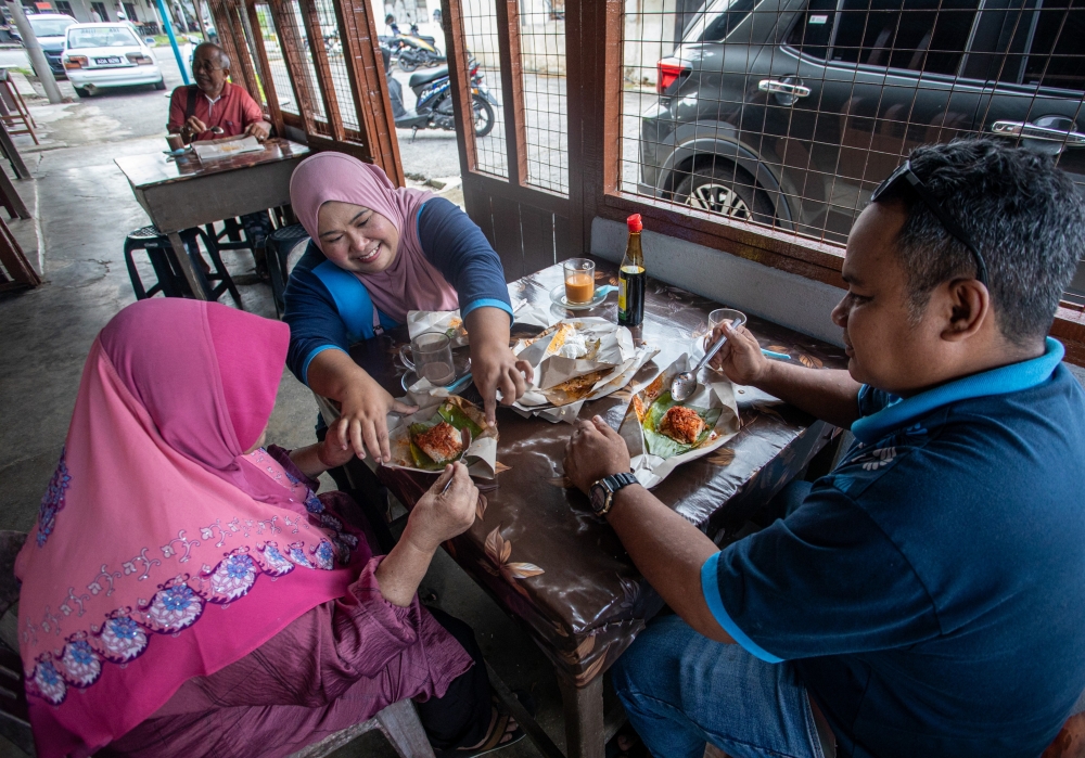 Patrons enjoying the 50 sen nasi lemak at Warung Lejen in Selama, Perak. — Bernama pic