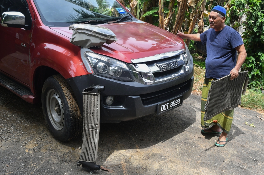 Produce wholesaler Ibrahim Ismail, 62, shows his damaged four-wheel drive after hitting a cow in Jeram Tekoh while returning from a night market, an incident that caused nearly RM4,000 in damages to his vehicle. — Bernama pic