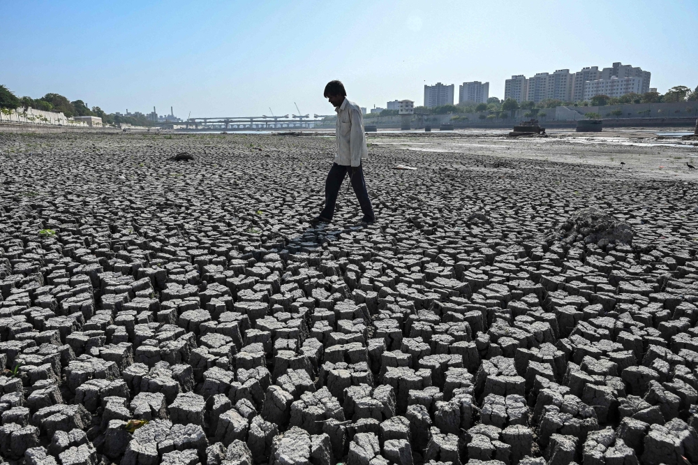 A man walks on the dry riverbed of the Sabarmati River in Ahmedabad on May 8, 2026. — AFP pic