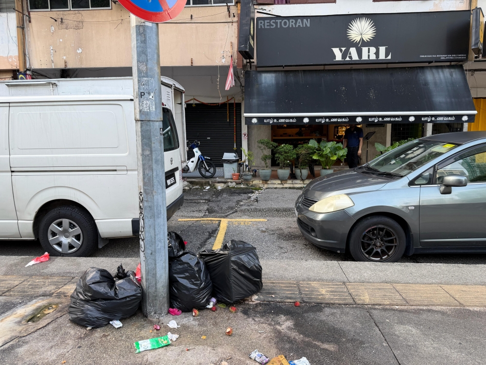 This is garbage piled on the pavement. Garbage blocking pedestrian paths. Garbage sitting under road signs.