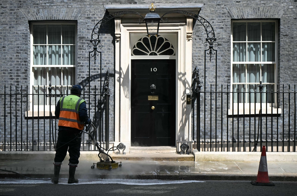 Workers clean the street outside the door to 10 Downing Street, the official residence of Britain’s Prime Minister Keir Starmer, in central London on May 9, 2026. — AFP pic