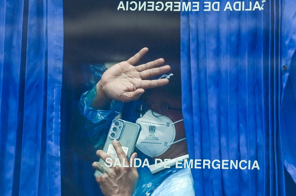 A passenger evacuated from the Dutch flagged hantavirus-stricken cruise ship MV Hondius waves aboard a military bus after being transferred by boat to the industrial port of Granadilla de Abona on the island of Tenerife in Spain's Canary Islands on May 10, 2026. — AFP pic 