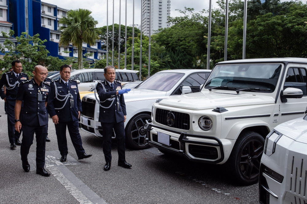 Inspector-General of Police Datuk Seri Mohd Khalid Ismail (right) showing some of the luxury vehicles seized from an international scam syndicate operating out of the Klang Valley during a press conference on Op Teguh 2.0 at the Bukit Aman police headquarters in Kuala Lumpur on May 15, 2026. — Bernama pic
