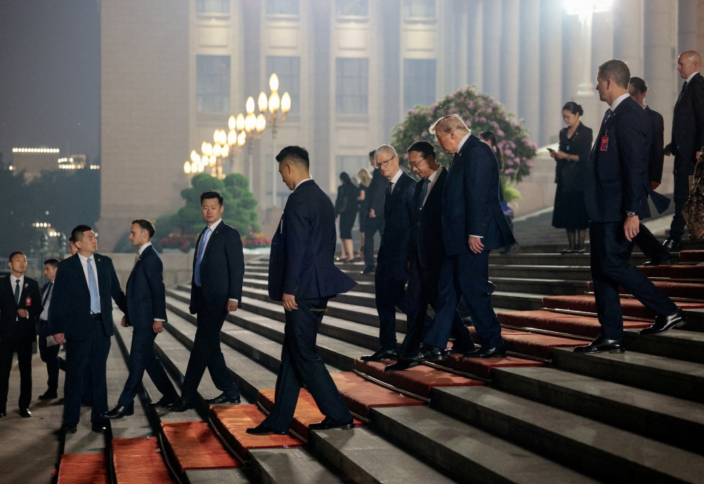 US President Donald Trump, Chinese Vice Foreign Minister Ma Zhaoxu and Apple CEO Tim Cook walk outside the Great Hall of the People after attending a state banquet in Beijing on May 14, 2026. — Reuters pic