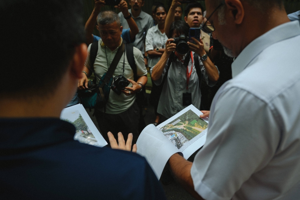 Damansara MP Gobind Singh Deo (right) looks at hillslope stability plans during a site inspection of an under-construction 26-storey condo at Damansara Perdana near Empire Residence with MBPJ engineering officials on May 15, 2026. — Picture from Facebook/Gobind Singh Deo