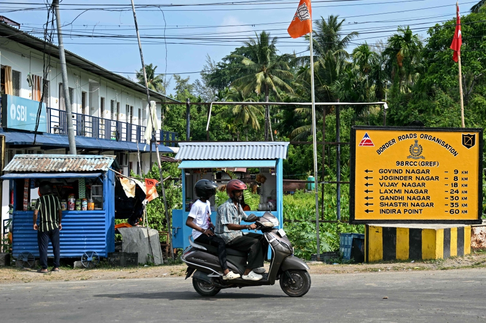 This photograph taken on March 28, 2026 shows a commuter riding past a Bharatiya Janata Party (BJP) flag set up next to roadside stalls along a street at Campbell Bay in Great Nicobar Island. — AFP pic 