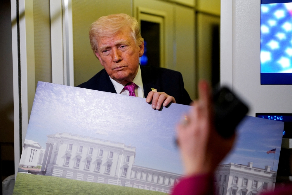 US President Donald Trump talks while holding up renderings of the planned White House ballroom as a member of the media raises her hand to ask a question aboard Air Force One en route to Joint Base Andrews, Maryland on March 29, 2026. — Reuters pic