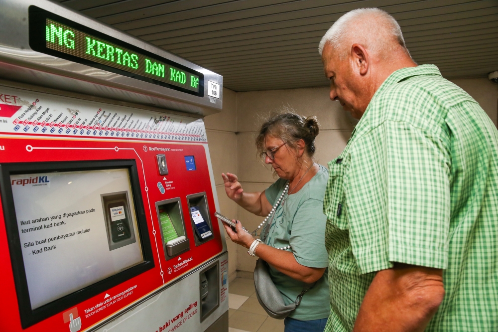 Tourists are seen here buying tokens at a ticket machine at an LRT station in Kuala Lumpur. — Picture by Choo Choy May