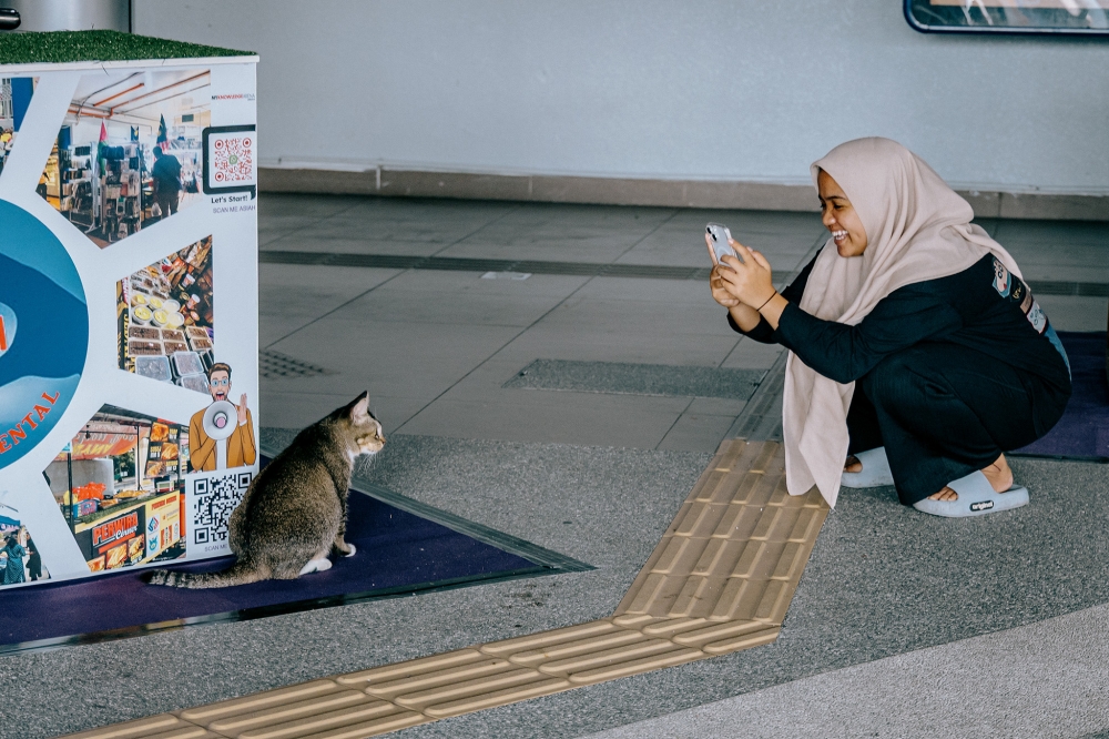 A commuter taking a photo of Kenit during off-peak hours at the LRT Ampang station. — Picture by Firdaus Latif