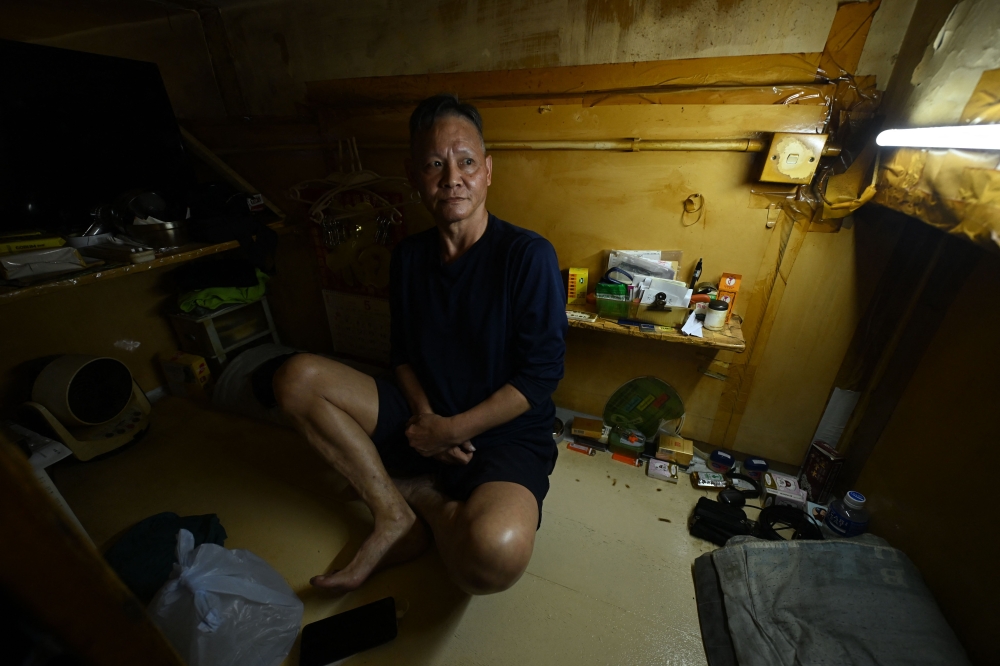 This photo taken on May 4, 2026 shows Wan Hon-cheung, 64, sitting in his so-called ‘cage home’ in a subdivided housing unit in Kowloon, Hong Kong. — AFP pic