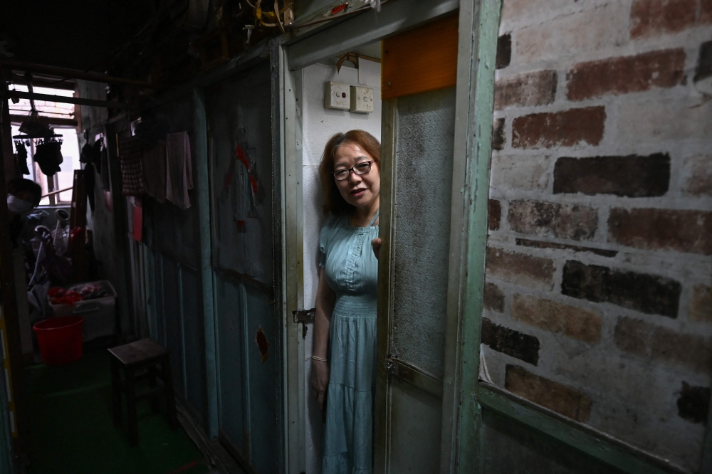 This photo taken on April 30, 2026 shows Liu Xiaoli, 63, looking out of her subdivided housing unit in Kowloon, Hong Kong. — AFP pic