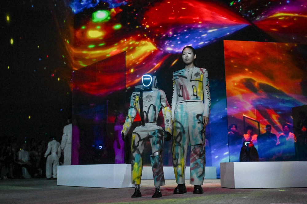 A humanoid robot and a model present creations at Galaxy Corporation’s ‘Mach33: Physical AI Fashion Show’ in Seoul on May 28, 2026. — AFP pic 