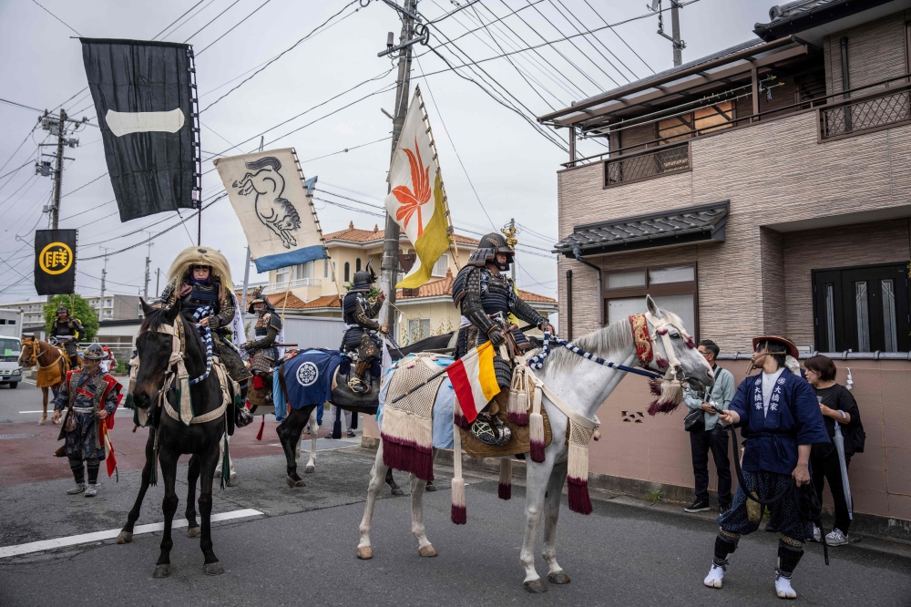 This picture taken on May 24, 2026 shows horsemen clad in samurai armor riding through a residential neighbourhood during the Soma Nomaoi festival in Minamisoma, Fukushima prefecture. — AFP pic