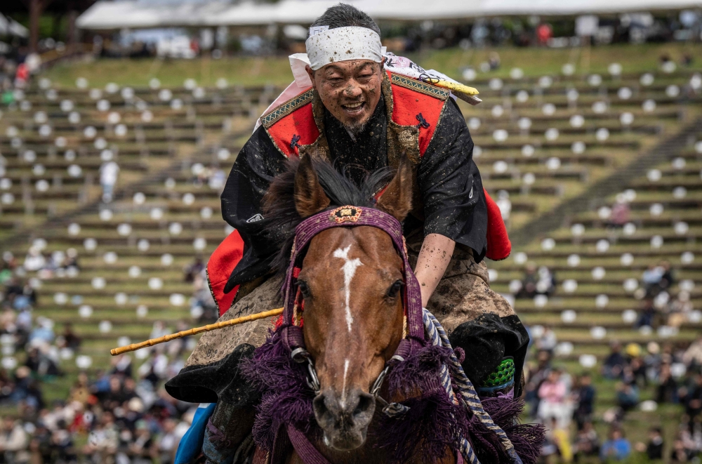 In this picture taken on May 23, 2026, a horseman clad in samurai armor reacts after competing in the Yoinori Keiba race during the Soma Nomaoi festival at Hibarigahara field in Minamisoma, Fukushima prefecture.