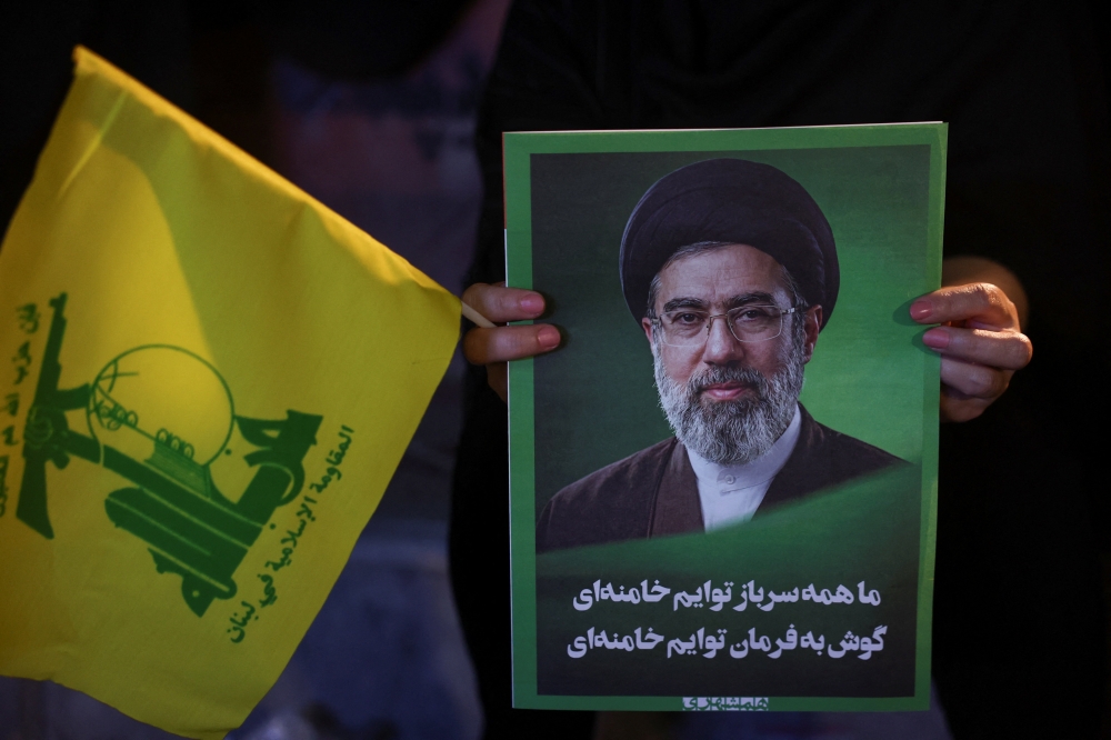 A woman holds an image of Iran's Supreme Leader, Mojtaba Khamenei, and a Hezbollah flag during a rally in Tehran June 1, 2026. — Majid Asgaripour/Wana (West Asia News Agency) pic via Reuters