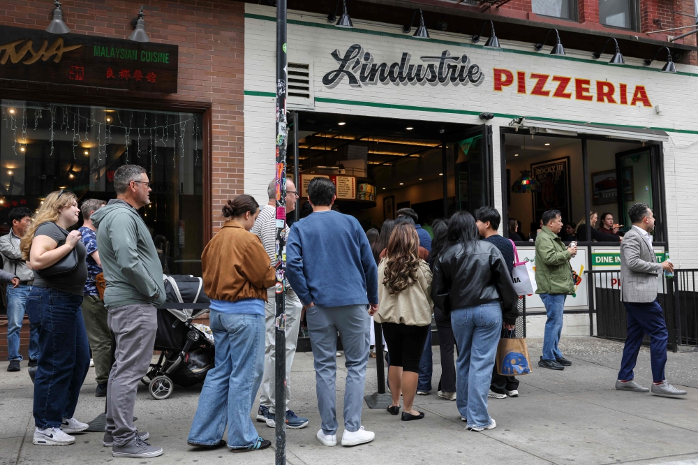 People wait in line outside L'industrie Pizzeria in New York City on May 15, 2026. In front of L'industrie Pizzeria, as at many other New York restaurants and shops, customers line up behind barriers -- in this case, all to grab a prized pizza slice. Not everyone in America's biggest city finds standing in line to be a chore. The power of social media trends means that for some, waiting for hours is an attraction in itself. — AFP pic