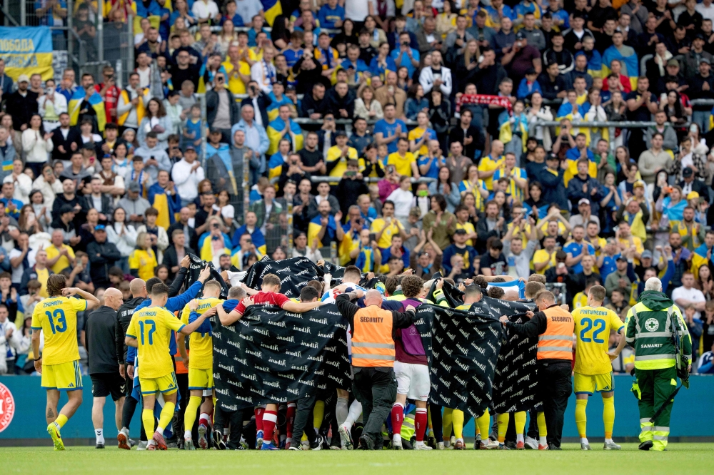 Denmark’s and Ukraine’s players huddle to accompany Christian Eriksen to a waiting ambulance during the football international friendly match between Denmark and Ukraine at Odense Stadium in Denmark, on June 7, 2026. — AFP pic