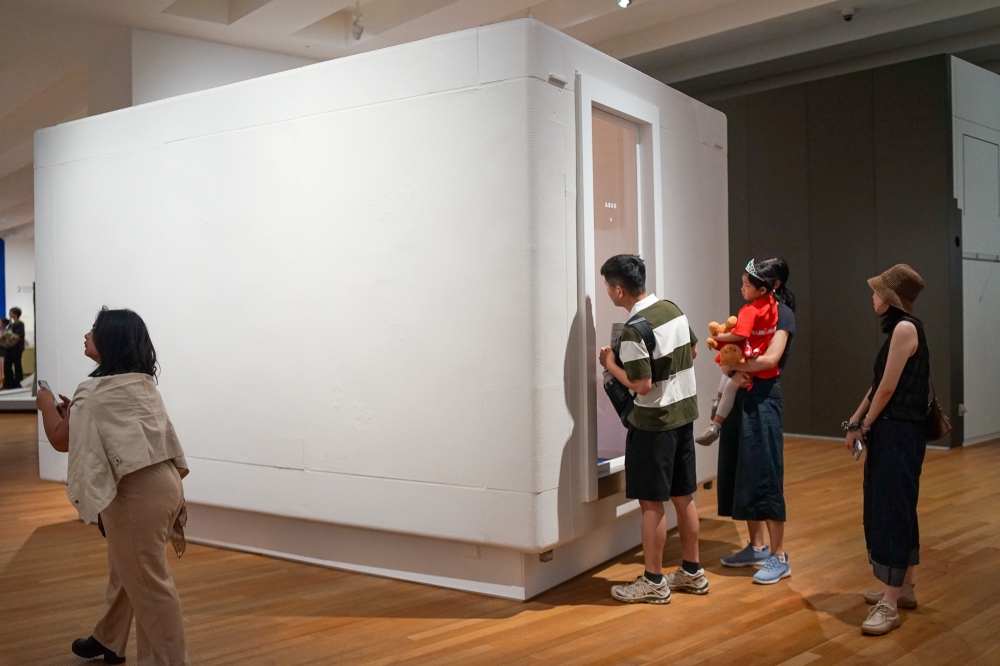 Visitors at M  peer into the restored Unit A806, an apartment unit which includes a bathroom despite measuring just 255 × 270 × 420 cm. — Picture by Ida Lim
