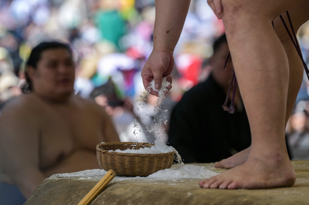 A sumo wrestler grabs a handful of salt as he takes part in the annual ‘honozumo’, a ceremonial one-day sumo exhibition for spectators held at Yasukuni Shrine in Tokyo in this file picture dated April 15, 2024. — AFP pic 