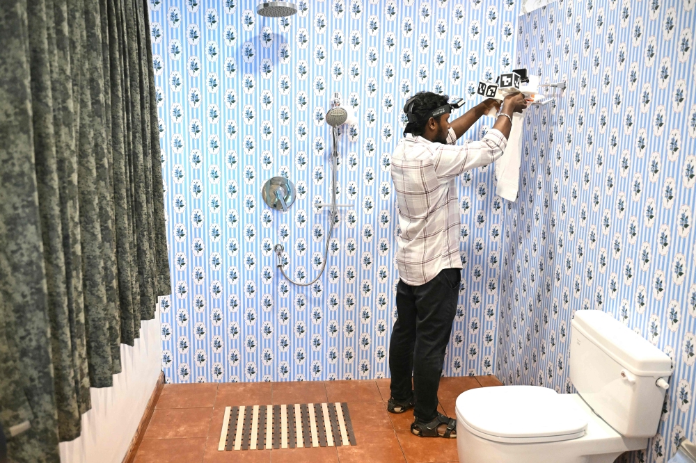 This photograph taken on May 13, 2026 shows a worker wearing a GoPro camera on his head recording actions through motion capture while folding towels inside a model bathroom at AI data company Objectways’ office in Tamil Nadu’s Karur district. — AFP pic 