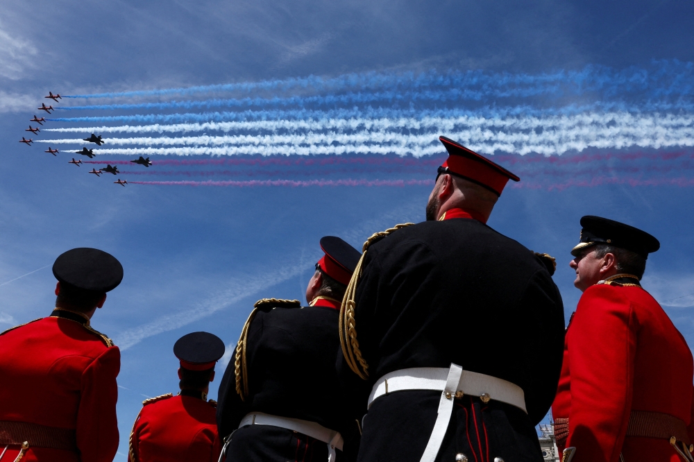 Members of the British military in ceremonial dress watch the Red Arrows flypast from Horse Guards Parade during Trooping the Colour, marking King Charles’s official birthday, in London, June 13, 2026. — Reuters pic