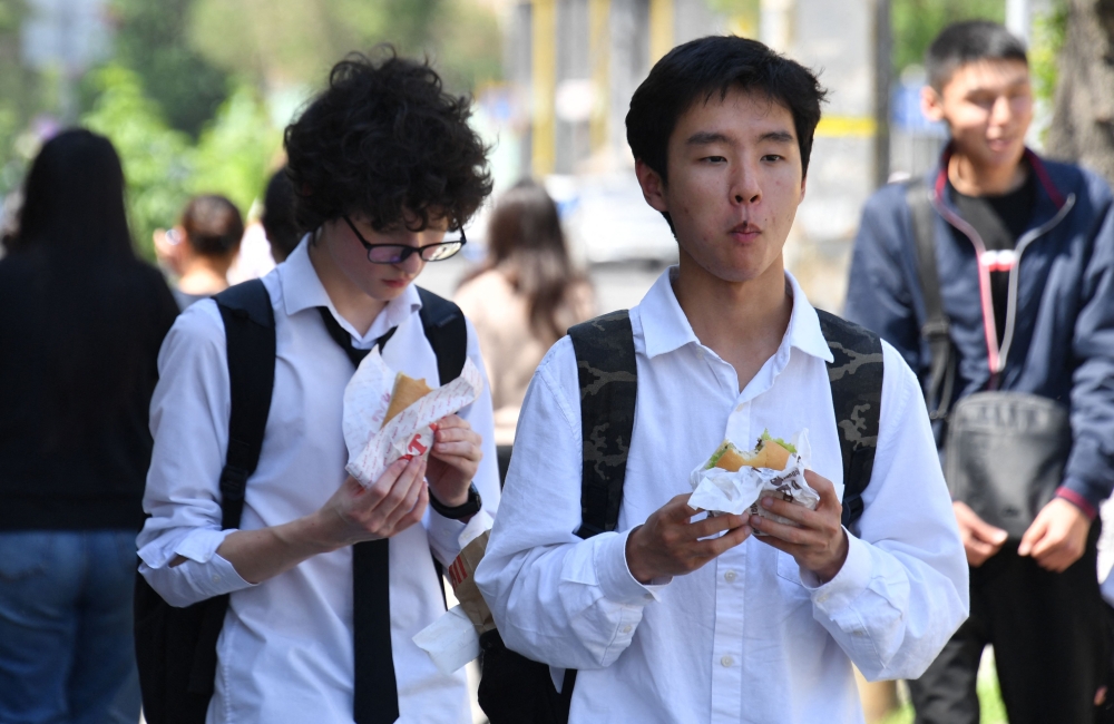 Kyrgyz youths eat fast food on a street in Bishkek on April 30, 2026. — AFP pic 