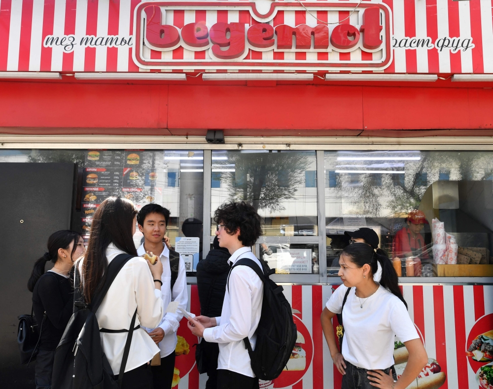 Kyrgyz youths eat fast food on a street in Bishkek on April 30, 2026. — AFP pic 