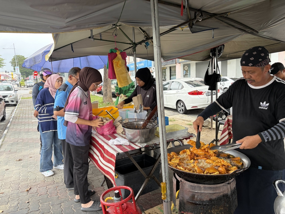 Anuar Othman fries up the ‘pisang goreng’ at his stall. — Picture by Opalyn Mok