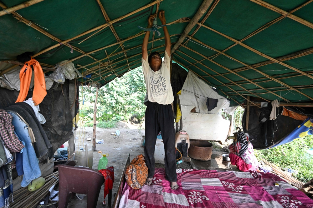 Farmer Bhole Shankar’s son,Tejpal attaches a portable electric fan to the beam inside his tent home on the Yamuna river floodplains in New Delhi on June 3, 2026 when temperatures cross 40°C. — AFP pic