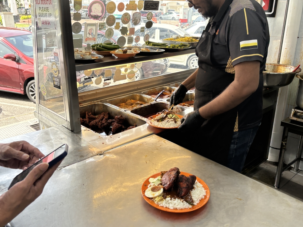 A worker in Nasi Kandar Dato Sagor in Ipoh preparing a plate of ‘nasi kandar’ for customers. — Picture by John Bunyan
