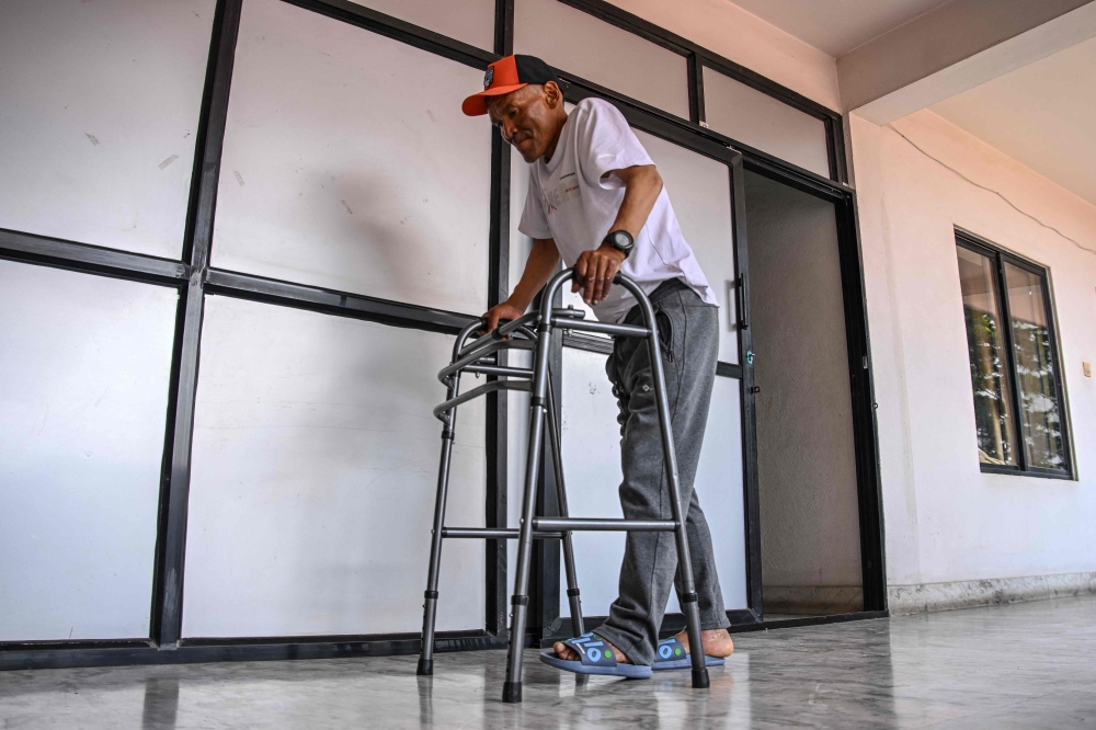 Everest survivor Dawa Sherpa walks with a support during his recovery in Kathmandu June 18, 2026. — AFP pic