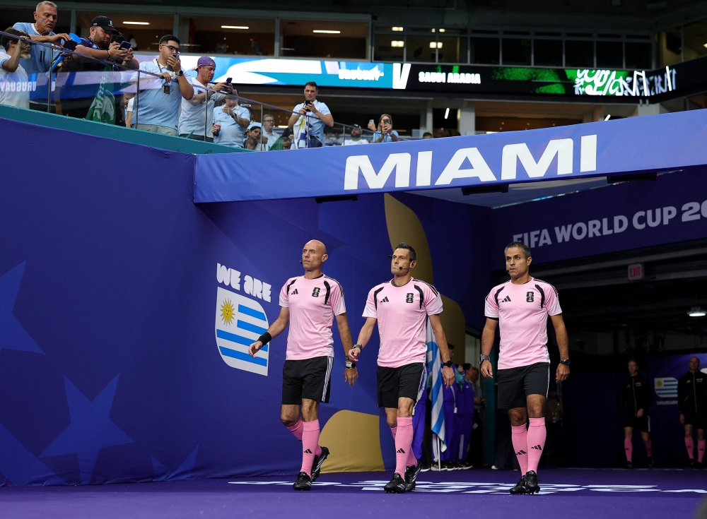 Referee Maurizio Mariani (centre) and match officials sport matching hot pink shirts before Saudi Arabia’s World Cup Group H match against Uruguay in Miami June 15, 2026. — AFP pic