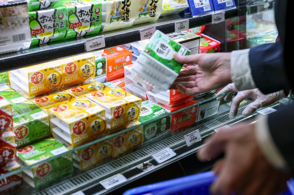 A shopper picks up packages of ‘natto’ at a Japanese grocery store in New York. — AFP pic