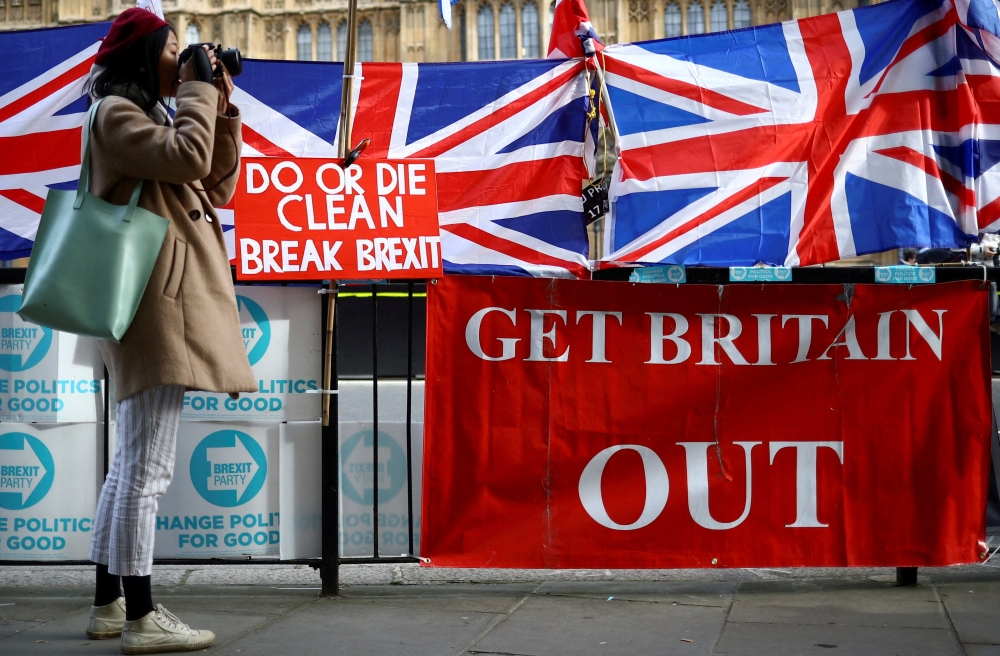 A woman takes pictures next to pro-Brexit placards outside the Houses of Parliament in London October 28, 2019. — Reuters pic