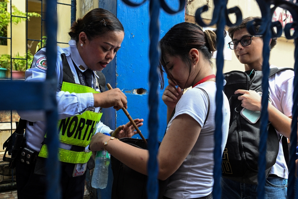 A security guard checks the bag of a student entering Batasan Hills National High School in Quezon City, Philippines on June 23, 2026. — Reuters pic