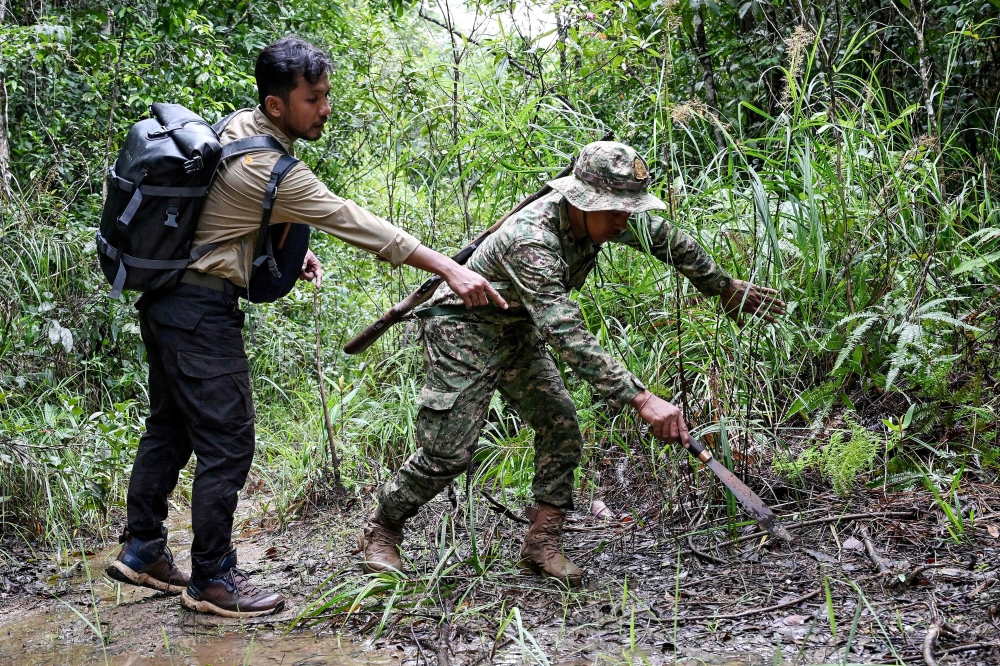 Biodiversity and Science Senior Coordinator of Conservation International Cambodia Chea Sareach (left), and ranger Hou Sophoan look at an animal footprint in the Cardamom National Park in Koh Kong province. — AFP pic 