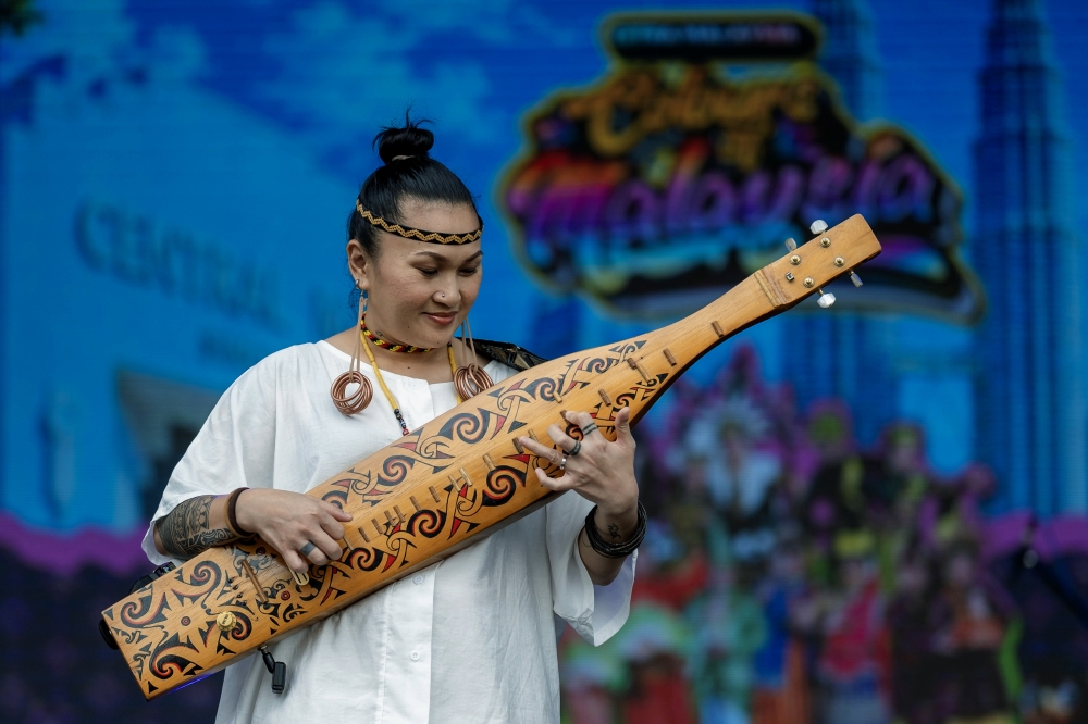 A performer with a traditional instrument, sape, at the 'Colours of Malaysia' event at Pasar Seni. — Bernama pic