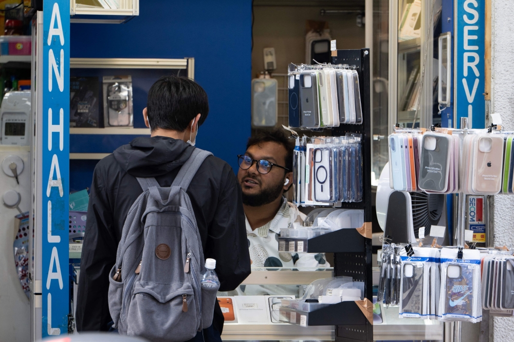A man goes to a phone repair shop in the Okubo亡hin area in Tokyo on June 12, 2026. Authorities late last year toughened requirements for business manager visas after reports many foreigners — chiefly Chinese nationals — were setting up shell companies to move to Japan. — AFP pic