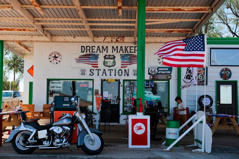 A US flag blows in the wind outside the Dream Maker Station Route 66 Souvenir & Gift Shop at the Route 66 midpoint on June 7, 2026 in Adrian, Texas. Whatever its means, the ‘American dream’ still offers hope to millions of people who believe the United States is a place where anyone can succeed, no matter the odds. — Heather Diehl/Getty Images North America pic via  AFP