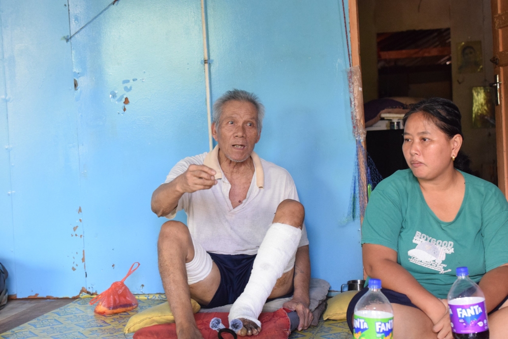 Liang (left) sharing his story of life and his infected leg to the visitors. — The Borneo Post pic