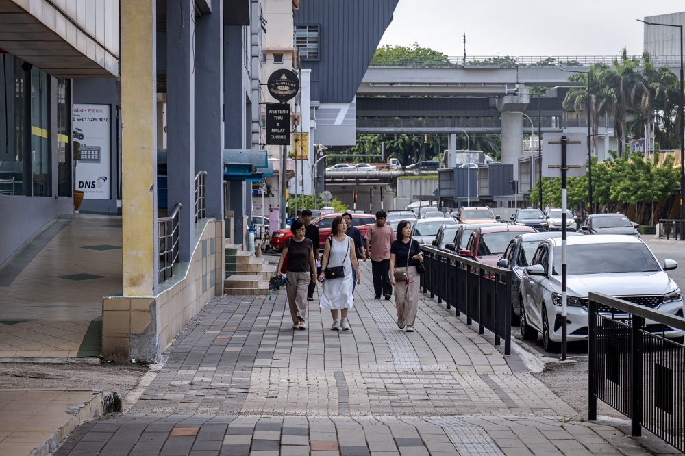 Malaysians walking on the upgraded pedestrian walkway while exploring Klang. — Picture by Firdaus Latif